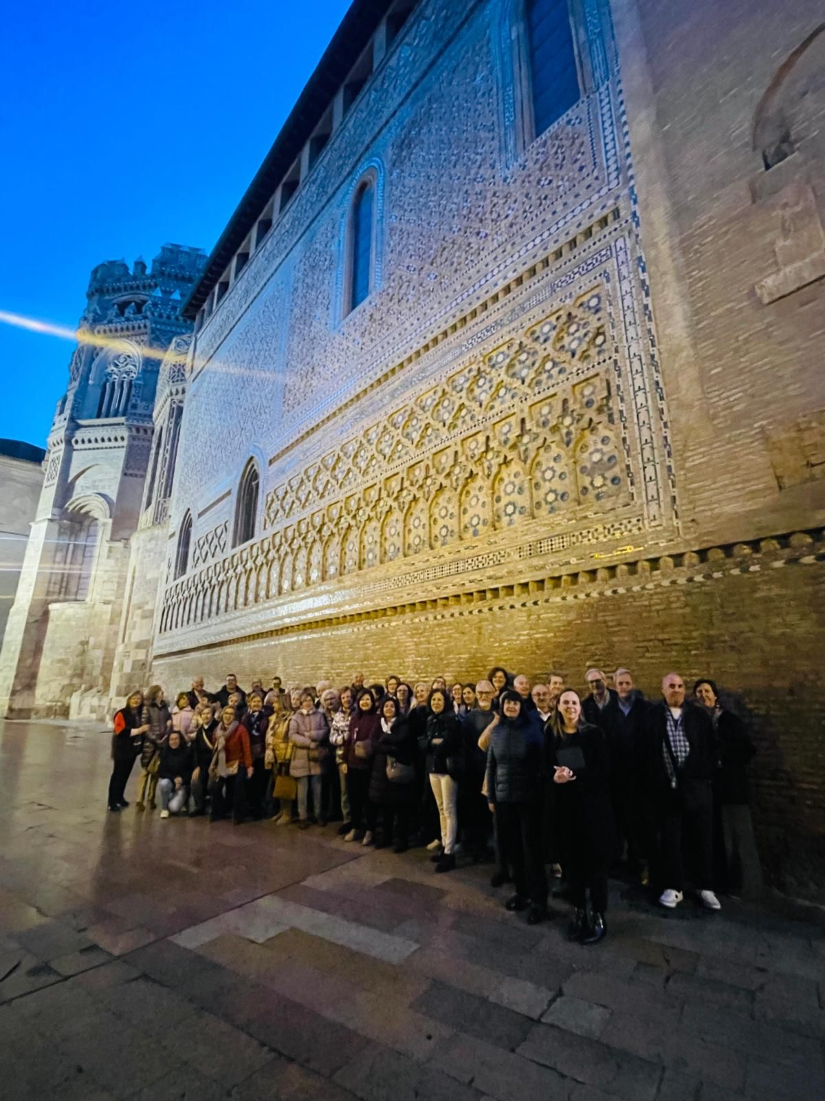 Grupo de estudiantes de la Universidad de la Experiencia frente al ábside mudéjar de la Parroquieta de La Seo en Zaragoza durante una visita guiada.