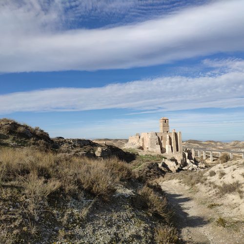 Vista de las ruinas del pueblo viejo de Rodén sobre una colina árida, con la iglesia y su torre destacando entre los restos.